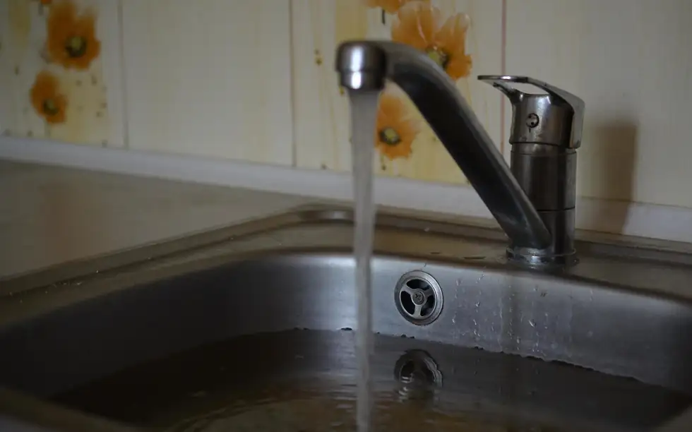 Kitchen sink with water standing in it while the tap runs
