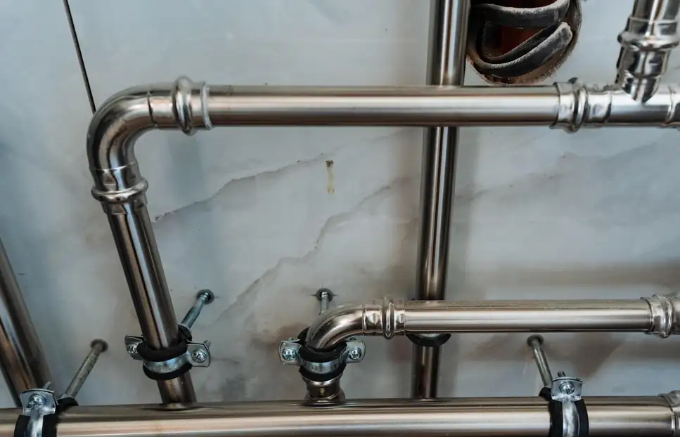 Stainless steel water pipes fixed to a tiled wall with pipe clips